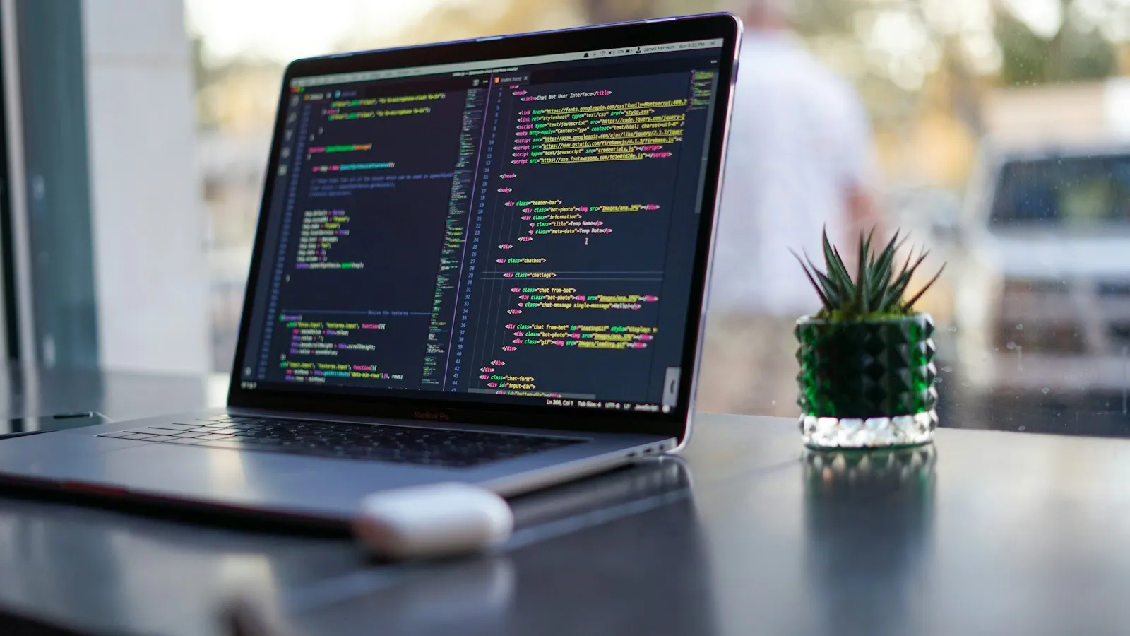 Laptop mit Programmcode auf einem dunklen Schreibtisch